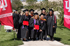A group of six IU Kokomo graduates smiles at the camera after commencement ceremonies.